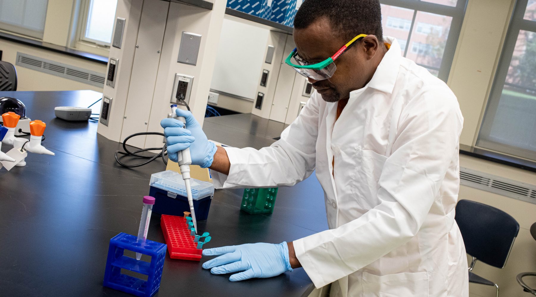 Man in lab coat performs lab work.