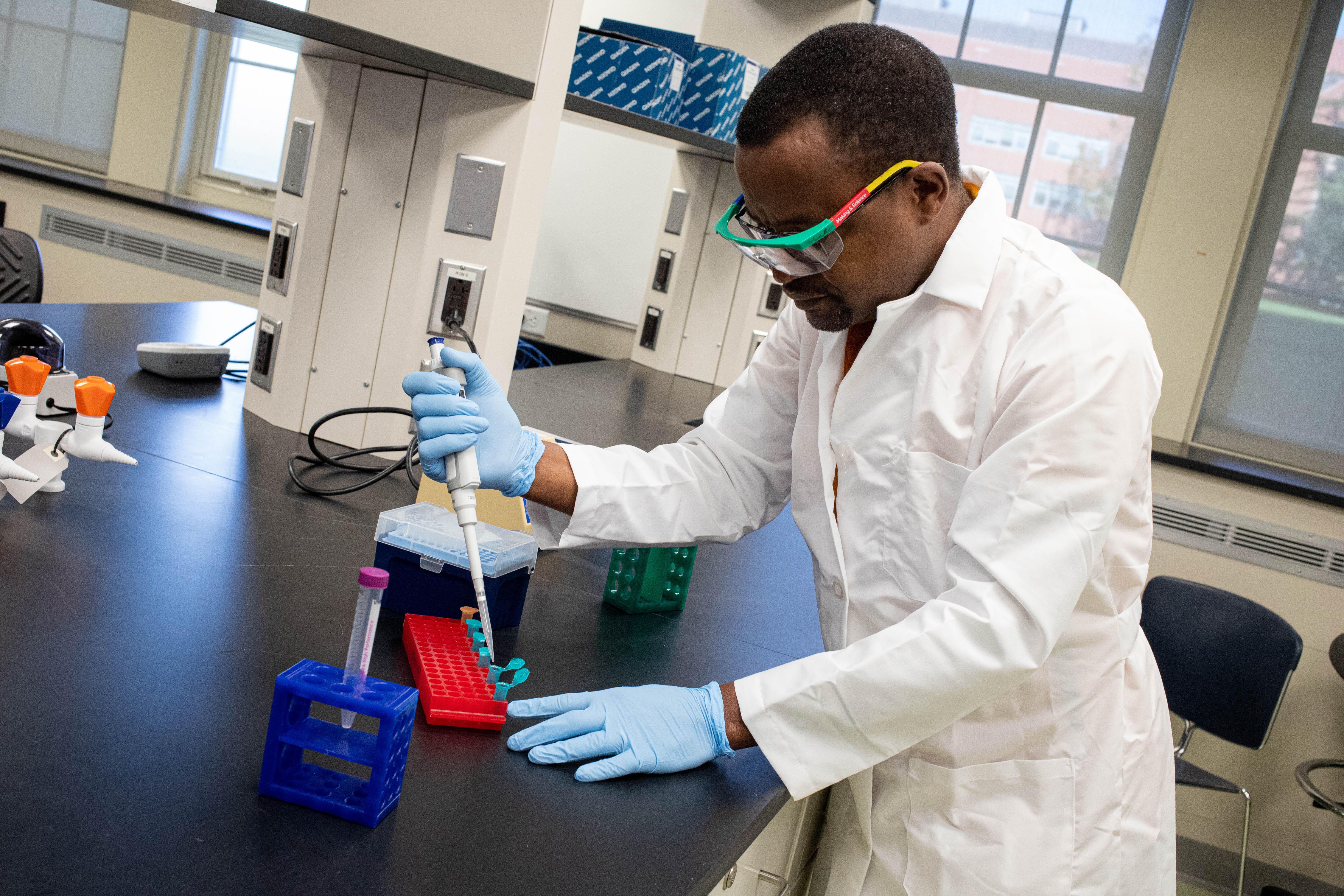 Man in lab coat performs lab work.
